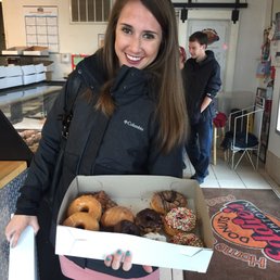 a woman holding a box of donuts a woman holding a box of donuts