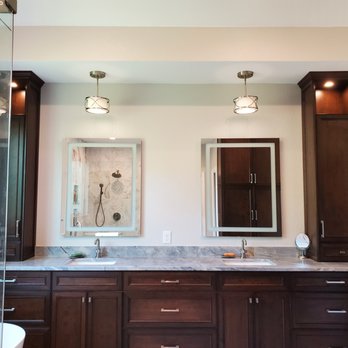 Capital City Tradesmen - a bathroom with dark wood cabinets and a marble countertop - General Contractors Near Me
