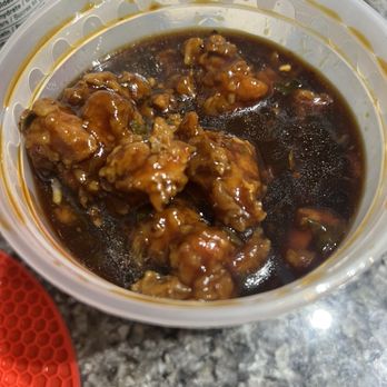 Federick Restaurant - A plastic container holds battered chicken pieces coated in a dark, glossy sauce, placed on a speckled countertop. - Chinese Near Me - Markham, Ontario