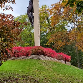Cross In the Woods - Back view of the Cross in the Woods Shrine. Beautiful Red Burning Bushes & Fall Flowers. 10/22/2019 - Churches Near Me - Indian River, Michigan