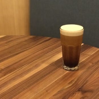 Dote Coffee Bar - a glass of coffee on a wooden table - Coffee & Tea Near Me - Bellevue, Washington