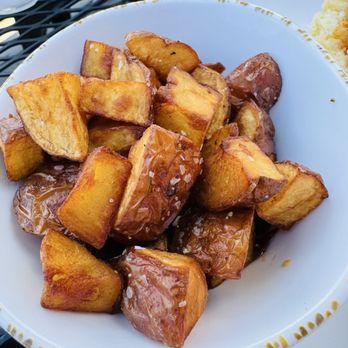 The Midwestern - Breakfast potatoes - A bowl filled with breakfast potatoes, featuring crispy, golden-brown chunks, served outdoors on a black metal table. - American Near Me - Saint Charles, Missouri