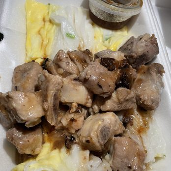 Big Fun Cafe - Steamed rice roll with spare ribs ADD egg - The image shows a foam takeout container with a steamed rice roll topped with spare ribs and egg. A small plastic cup of soy sauce is included in the container. The rice roll appears soft and slightly translucent, with the ribs and egg providing additional texture and flavor. Condiments like soy sauce are visible, and the food is arranged for easy takeaway consumption. - Cantonese Near Me - Quincy, Massachusetts