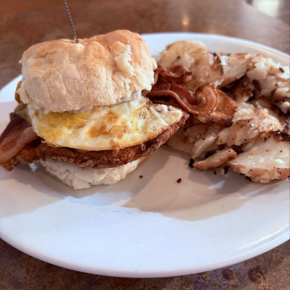 HH Breakfast Sandwich: biscuit with chicken fried chicken, gravy, bacon, and egg with a side of potato