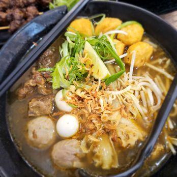 Barzar Eatery - Soto Madura (beef noodle soup). Beef skewers in the background. - Indonesian Near Me - Vacaville, California Barzar Eatery - Soto Madura (beef noodle soup). Beef skewers in the background. - Indonesian Near Me - Vacaville, California