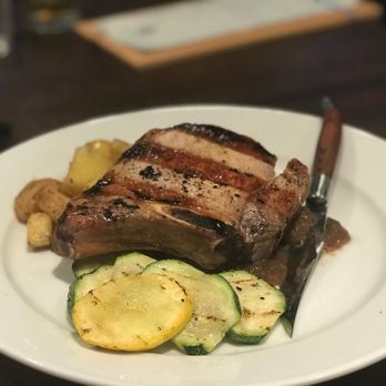 Sierra Grill - Pork Chop with potatoes and zucchini served with an in house applesauce. - Steakhouses Near Me - Lenexa, Kansas Sierra Grill - Pork Chop with potatoes and zucchini served with an in house applesauce. - Steakhouses Near Me - Lenexa, Kansas