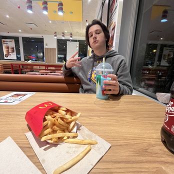 McDonald's - a woman sitting at a table with french fries - Fast Food Near Me - Chicopee, Massachusetts