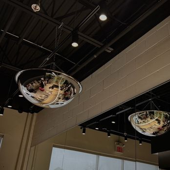 Matcha Matcha - interior - Two shiny, metallic, spherical objects are hanging from the ceiling of an indoor space. The spheres are suspended by chains and reflect the surrounding interior, including furniture, lighting, and people. The ceiling features exposed black structural elements and spotlights, with a wall and window visible in the background. - Coffee & Tea Near Me - Markham, Ontario
