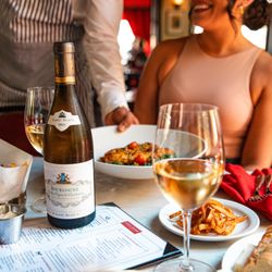 Bottle and glasses of white wine served alongside French dishes and fries at Toulouse.