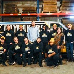 Daymakers Moving & Storage - Daymakers Moving & Storage team posing in warehouse in Bloomington, MN in front of branded moving truck and stacked boxes