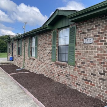 Pro Services Handyman - After - A single-story brick building with green shutters and a green gutter system, featuring a landscaped area with freshly mulched beds. - Handyman Near Me - Franklin, Tennessee