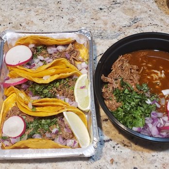 Sunnyside Eats - Birria ramen and Birria tacos - The image shows a meal on a granite countertop at Sunnyside Eats, featuring three tacos with yellow shells, garnished with radish slices, onions, and cilantro, along with a bowl of soup containing vegetables and herbs. Small containers of sauces and pickled onions are also visible. The setting suggests a casual dining or takeout environment with a focus on diverse cuisine options. - Food Delivery Services Near Me - Sunnyside, New York