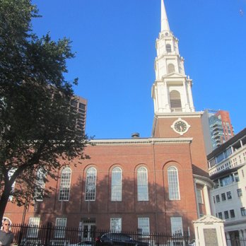 Boston Common - A brick church with arched windows and a tall white steeple, surrounded by trees and modern buildings, under a bright blue sky. - Parks Near Me - Boston, Massachusetts