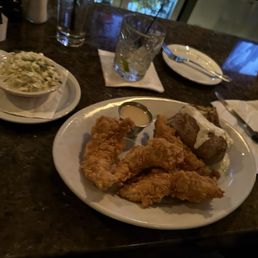 Chicken tenders - Plate of fried chicken tenders with dipping sauce, served with a baked potato topped with sour cream and a side of coleslaw.