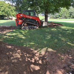John's Bobcat Services - Carefully spreading topsoil around existing trees.