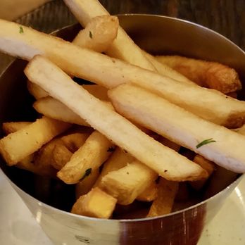Roosters - Side of fries - A metal cup contains French fries, some with herbs, with a mix of golden and slightly darker pieces. - Chicken Wings Near Me - Glenside, Pennsylvania