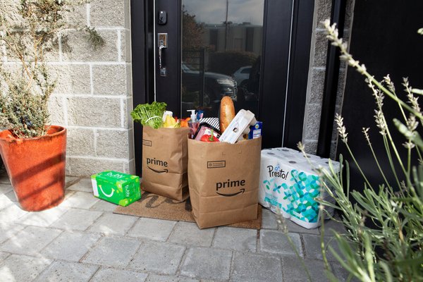 An Amazon Fresh delivery bag containing fresh groceries at a customer's doorstep, symbolizing the convenience of modern grocery shopping. (yelpcdn.com)