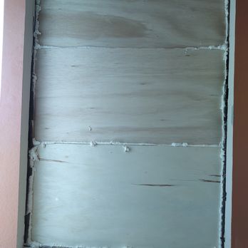 Window World of Albuquerque - Front inside - A window opening is covered with plywood panels, with foam insulation around the edges, set in a wall with a peach-colored exterior. - Windows Installation Near Me - Albuquerque, New Mexico