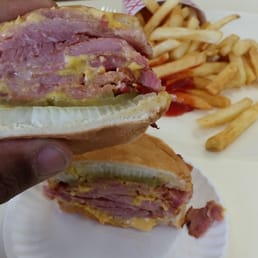 a hand holding a sandwich and french fries