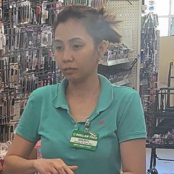 Dollar Tree - This Lady always treats us differently because we are a minority. She always ignores us when we ask for help and wont even say hello at the - A woman with dark hair tied back, wearing a teal polo shirt and a name tag, is inside a Dollar Tree store with shelves of merchandise in the background. - Discount Store Near Me - Pleasanton, California