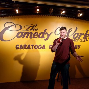 The Comedy Works - a man standing in front of a microphone - Comedy Clubs Near Me - Saratoga Springs, New York The Comedy Works - a man standing in front of a microphone - Comedy Clubs Near Me - Saratoga Springs, New York