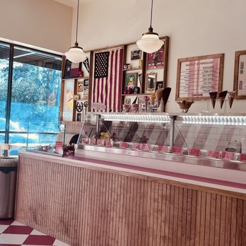 Oddfellows - Entrance - Ice cream parlor featuring a wooden counter, glass display, and patriotic decorations including an American flag and framed pictures. - Ice Cream & Frozen Yogurt Near Me - Spring, Texas
