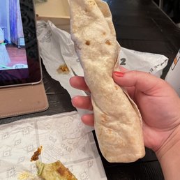 a person holding a burrito in their hand a person holding a burrito in their hand