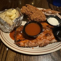 Ribs & Fried Chicken both excellent - A meal featuring barbecue ribs, fried chicken, mashed potatoes with butter, and two dipping sauces on a ceramic plate.