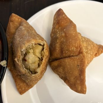 Shan Restaurant - Samosa 2Pc - Two fried samosas on a white plate, one cut open to show a potato filling inside. - Indian Near Me - Chicago, Illinois