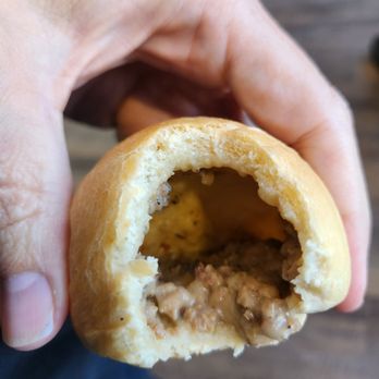 Kolache Factory - a hand holding a half eaten sandwich - Bakeries Near Me - Houston, Texas