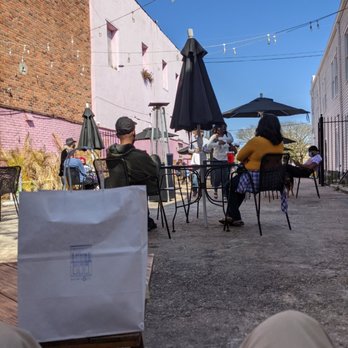 Baldwin & Co. - a group of people sitting at tables with umbrellas - Bookstores Near Me - New Orleans, Louisiana