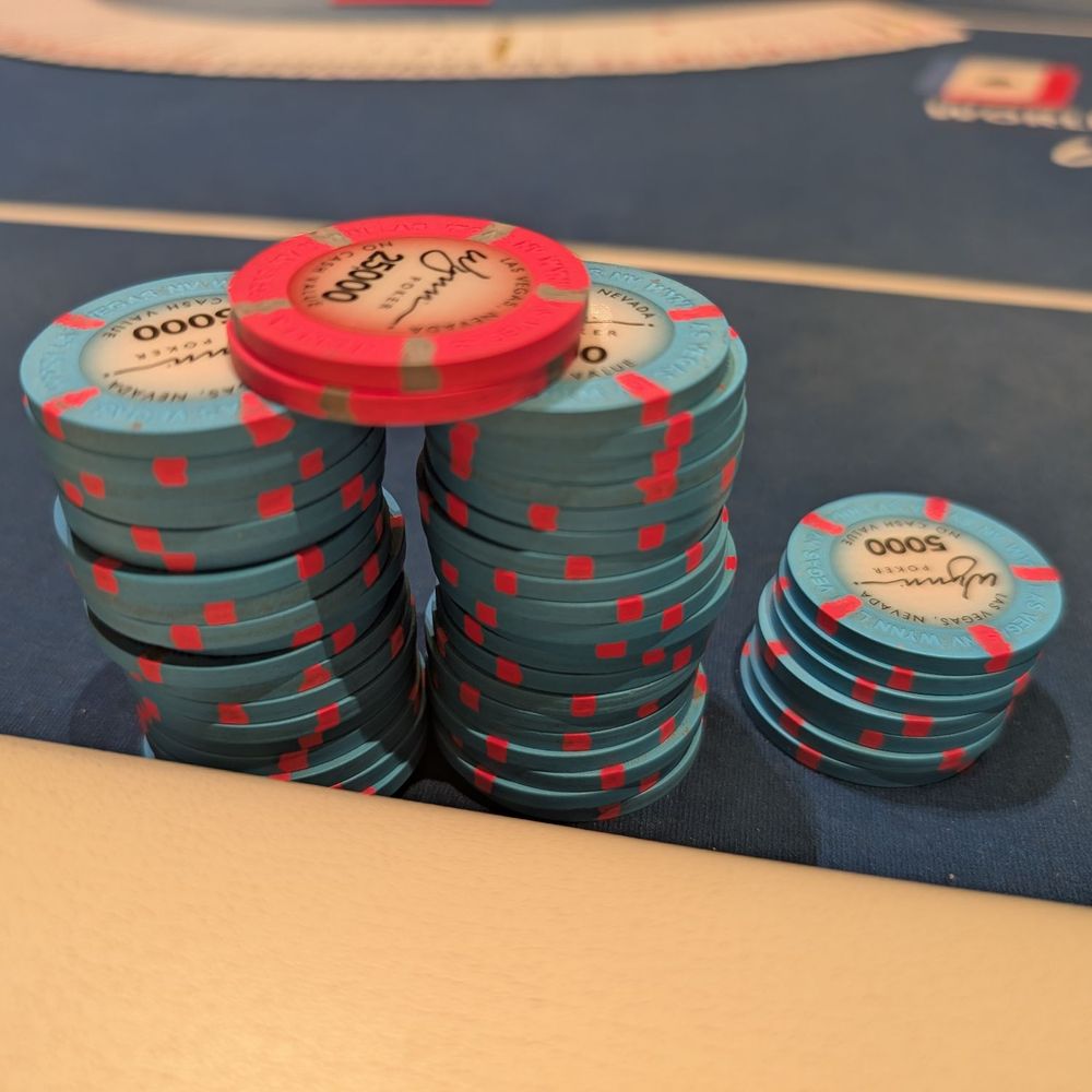 Eine Nahaufnahme von professionellen Poker-Händen, Chips und Karten auf einem grünen Tisch, symbolisierende strategische Entscheidungsfindung.