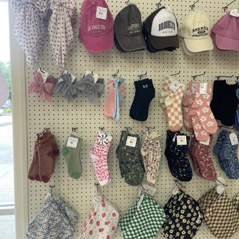 Indy clover - The image shows a pegboard wall with socks, hats, and hair accessories arranged in rows, including baseball caps, scrunchies, and patterned socks. - Thrift Stores Near Me - Plano, Texas