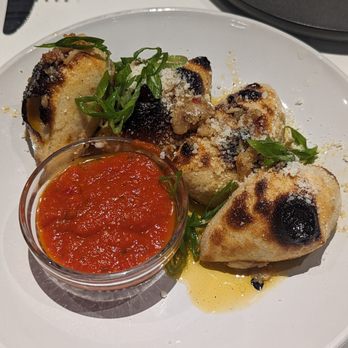 Il Mago - Sourdough garlic knots - Garlic knots stuffed with cheese, garnished with green onions, served with a side of marinara sauce on a white plate. - Pizza Near Me - Edwards, Colorado