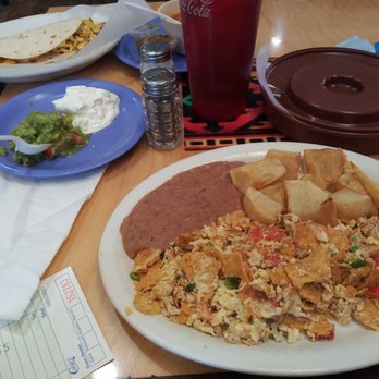 Taqueria El Tapatio - Migas Place plate with potatoes and beans plus tortillas. Sides of guacamole and sour cream. Taquito in the back. - Mexican Near Me - Amarillo, Texas