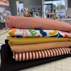 LA Finch Fabrics - Stack of designer overstock excess fashion fabrics. One of a kind unique apparel fabrics -seersucker, cotton gauze ,linen, hemp cotton,