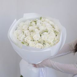 Divine Fleurs - A full bouquet of fresh white roses, paired with delicate filler flowers and wrapped in matching white paper. A timeless and elegant choice