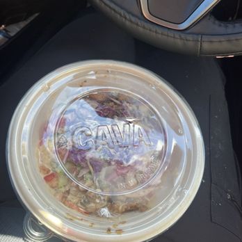CAVA - A salad in a transparent plastic container labeled 'CAVA' is placed on a car seat, with part of a steering wheel visible. - Mediterranean Near Me - Georgetown, Texas