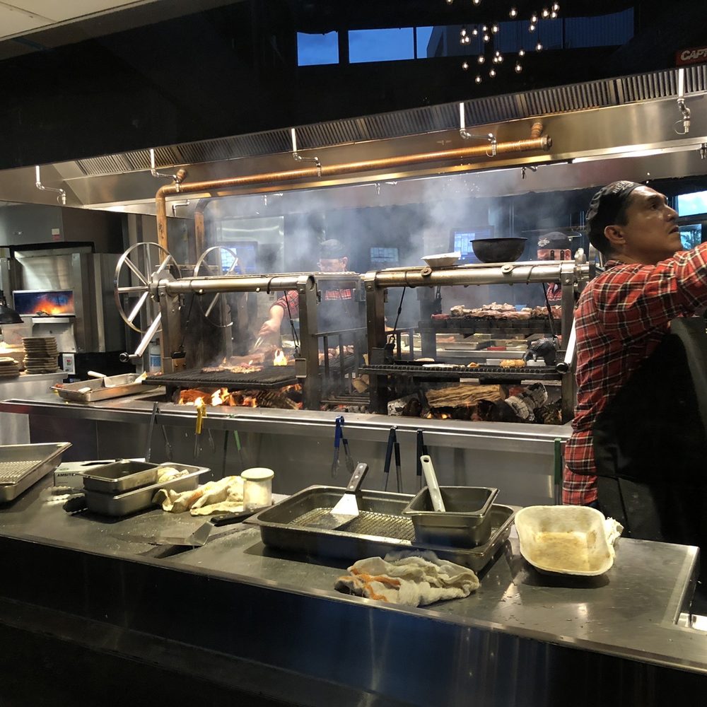 Bigfire - View of the grill through glass in the dining room - American Near Me - Orlando, Florida Bigfire - View of the grill through glass in the dining room - American Near Me - Orlando, Florida