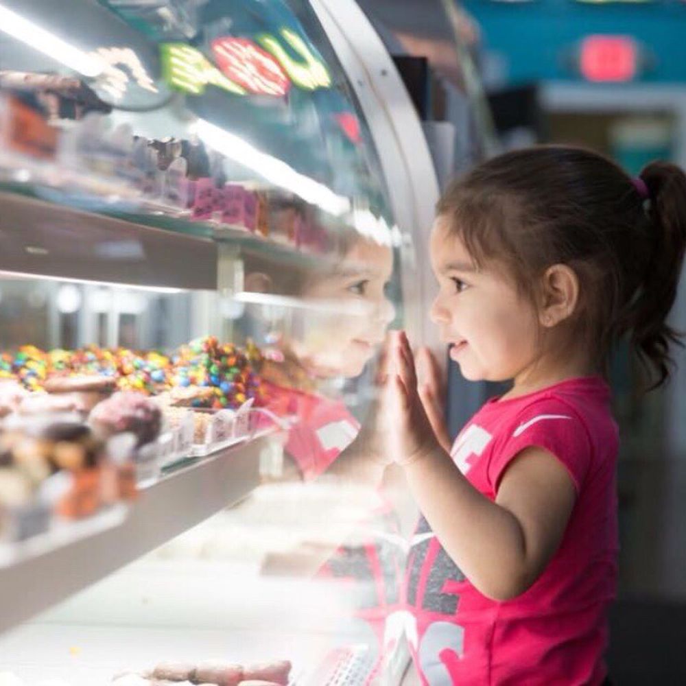 a little girl looking at a display of donuts a little girl looking at a display of donuts