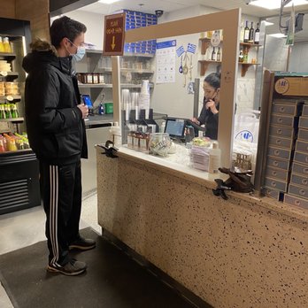 Gyro City - An employee touching her mask while handling payment, after pulling it down to speak with the guest, inside, food - Greek Near Me - Boston, Massachusetts