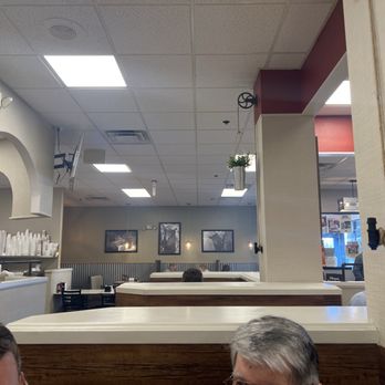 Red Squirrel - My camera can actually see the smoke - The image shows the interior of a casual restaurant with a drop ceiling featuring square fluorescent lights. Wall art depicting animals is visible on the back wall. Patrons are seated at tables, with some visible at the bottom of the image. The decor includes a hanging plant and a partition wall, and part of the counter area with cups and equipment is seen on the left. The setting appears to be a relaxed dining environment. - Diners Near Me - Cincinnati, Ohio