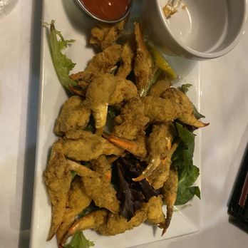 Half Shell Oyster House - Crab claws. Portion size not worth the price - Crab claws are fried and arranged on a rectangular plate with leafy greens, accompanied by a small bowl of red dipping sauce. - Seafood Near Me - Flowood, Mississippi