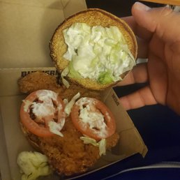 a hand holding a sandwich with lettuce and tomatoes a hand holding a sandwich with lettuce and tomatoes