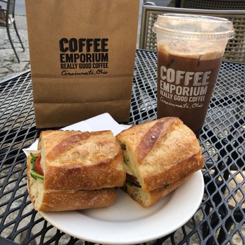 Coffee Emporium - Coffee Emporium bag holding Fudge-flavored coffee grounds, a Brew Hoo, and a pesto sandwich. - Coffee & Tea Near Me - Cincinnati, Ohio Coffee Emporium - Coffee Emporium bag holding Fudge-flavored coffee grounds, a Brew Hoo, and a pesto sandwich. - Coffee & Tea Near Me - Cincinnati, Ohio