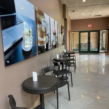 Holiday Inn Manitowoc - Tables to sit across from the self serve coffee bar serving up a selection of Starbucks. - Hotels Near Me - Manitowoc, Wisconsin