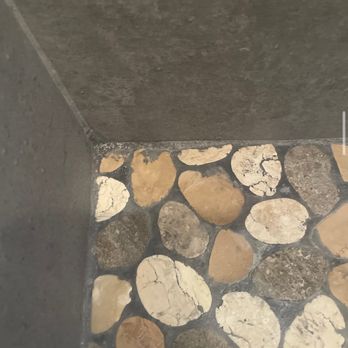 Innovative Home Improvement - a shower with pebbles on the floor - Painters Near Me - Teaneck, New Jersey