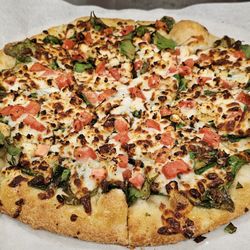 A spinach pizza with tomato garlic and feta cheese. i added chicken