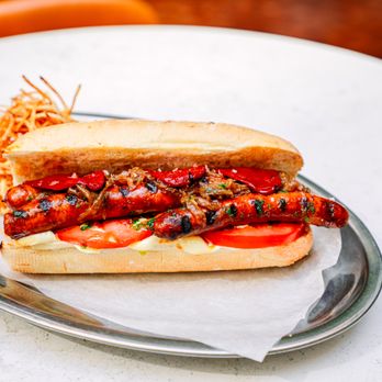 Brasa by Casa Teresa - Txistorra dog: skinny Navarra pork sausage, caramelized onions, allioli sauce, piquillo peppers, tomatoes - Spanish Near Me - Washington, DC, District of Columbia Brasa by Casa Teresa - Txistorra dog: skinny Navarra pork sausage, caramelized onions, allioli sauce, piquillo peppers, tomatoes - Spanish Near Me - Washington, DC, District of Columbia
