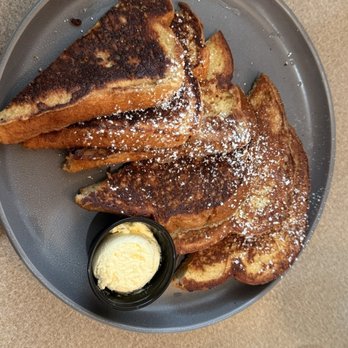 The Brunch House - French Toast with Butter - French toast slices dusted with powdered sugar, served with a small dish of butter on a gray plate at a restaurant. - Breakfast & Brunch Near Me - Redding, California